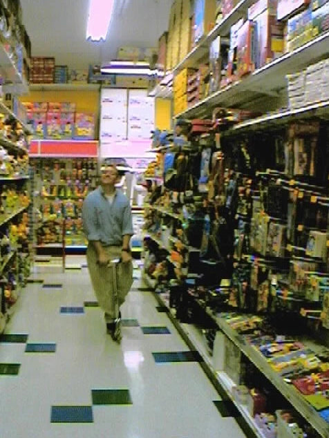 A shopper standing in a colorful toy-store aisle.